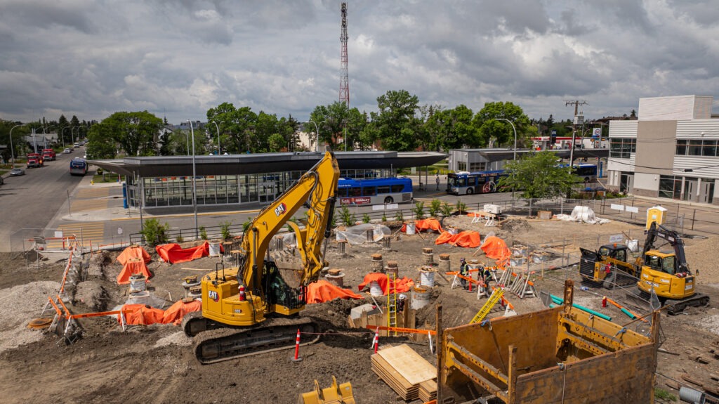 GS Construction crew and excavator working near a bus station during underground utility construction in Edmonton