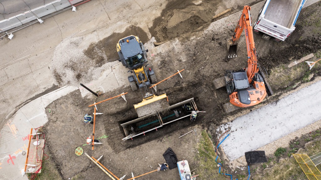Aerial view of gravel being placed into a shored excavation during West Valley LRT underground infrastructure work