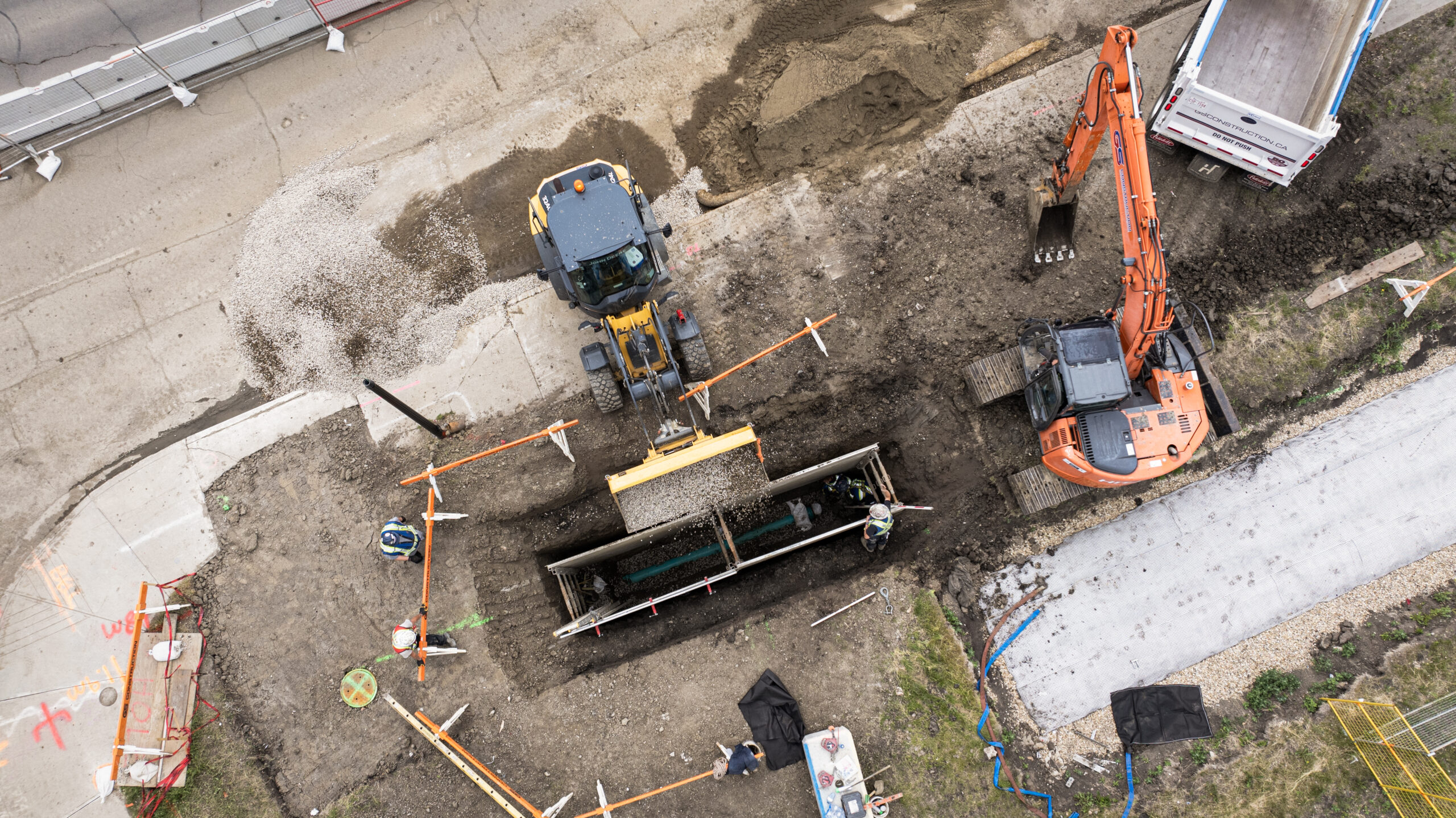 Aerial view of gravel being placed into a shored excavation during West Valley LRT underground infrastructure work