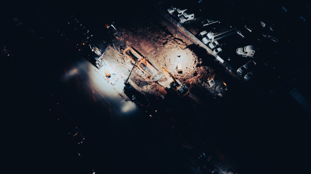 Nighttime construction work on transmission main repair with illuminated excavation site