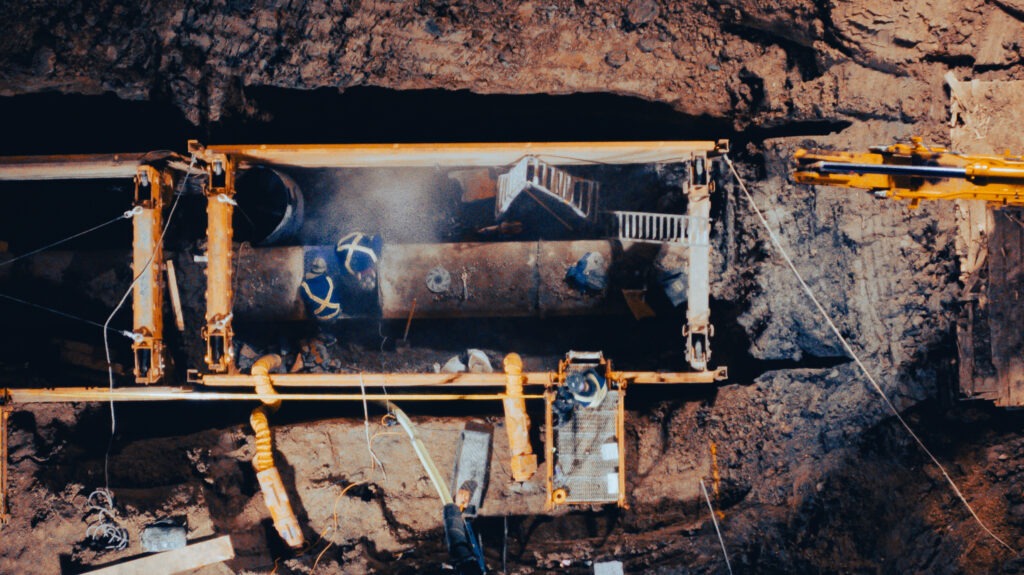 Close-up of exposed transmission main pipe within shoring system during repair work