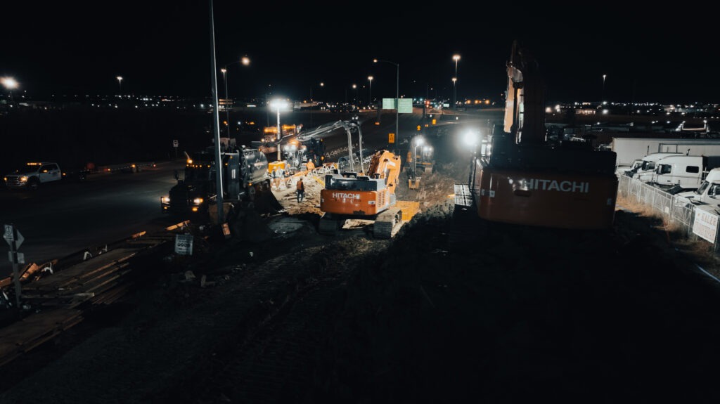 Night shift operations with excavators working on watermain repair along major roadway
