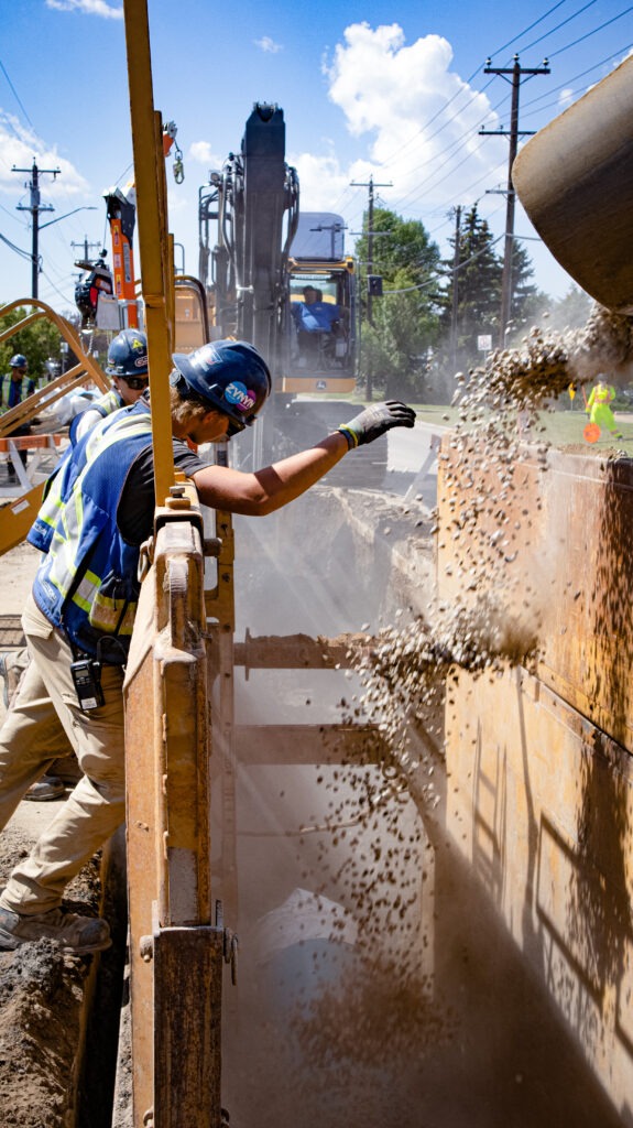 Worker guiding backfill operations during watermain installation