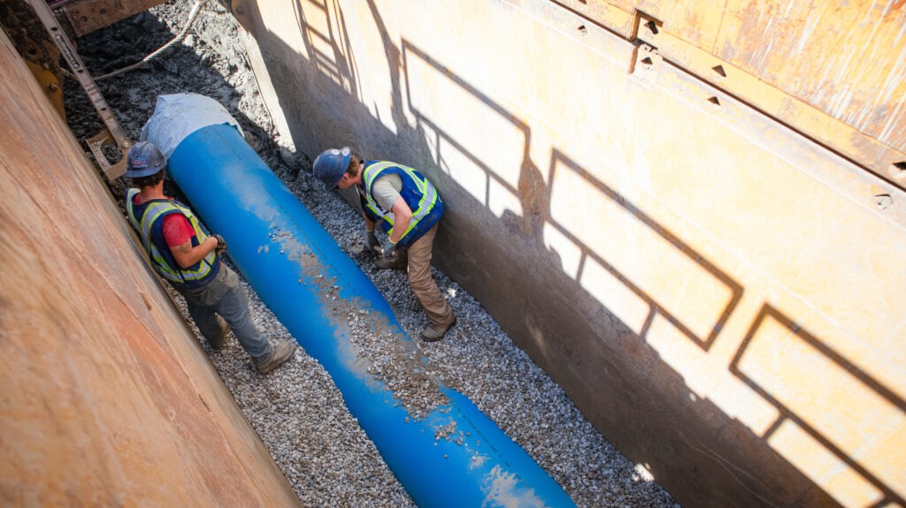 Crew working inside trench installing large diameter watermain pipe