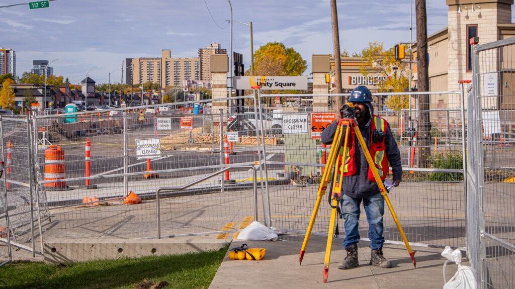 GS Construction crew member using a survey theodolite on the MacEwan University construction site
