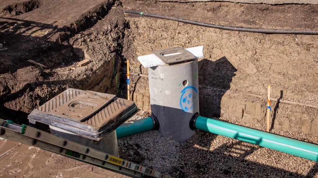 Two catch basins connected by underground piping in an open trench