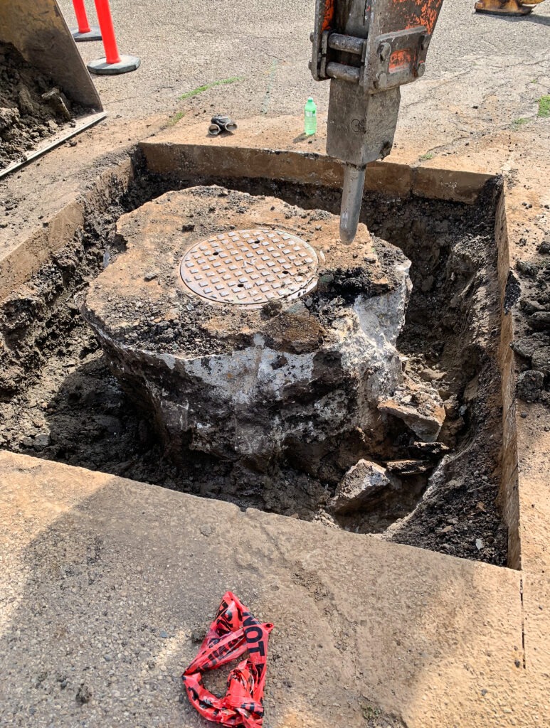 Street surface removal around an existing manhole at the start of SIRP manhole repair work